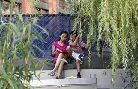 Karen Cheng, 13, and Mike Huang, 9, both of Chinatown, read along the Greenway in their neighborhood. 
